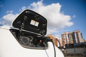 opladen modern elektrisch auto accu Aan de straat welke zijn de toekomst van de auto, dichtbij omhoog van macht levering aangesloten in een elektrisch auto wezen opgeladen voor hybride . nieuw tijdperk van voertuig brandstof. foto