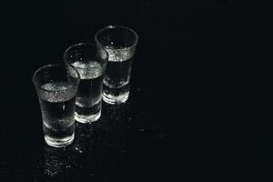 wodka. schoten, bril met wodka met ijs .donker achtergrond. kopiëren ruimte .selectief focus. foto