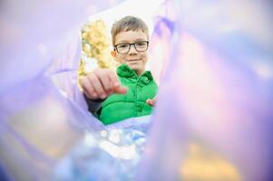 jongen gooit plastic uitschot in een zak in de park foto