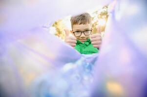 jongen gooit plastic uitschot in een zak in de park foto