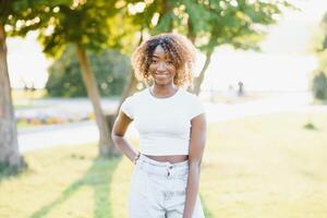 schattig zwart vrouw glimlachen in een park foto