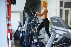 aantrekkelijke jonge sportvrouw werkt in de sportschool. cardiotraining doen op de loopband. lopen op de loopband. foto