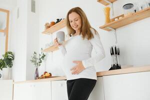 jong zwanger vrouw drinken thee in keuken foto