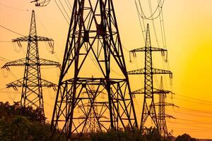 transmissie lijnen Aan achtergrond van industrie elektriciteit torens. zonsondergang silhouet hoog Spanning elektrisch torens. foto