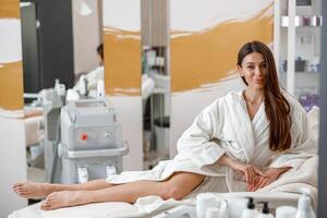 vrouw in wit badjas glimlachen in spa centrum Aan schoonheid behandelingen foto