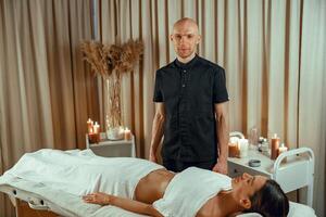 professioneel mannetje masseur aan het doen massage naar vrouw cliënt in spa salon. kom tot rust concept foto