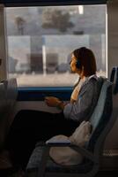 vrouw in hoofdtelefoons terwijl op reis in openbaar vervoer en op zoek visie buiten de venster foto