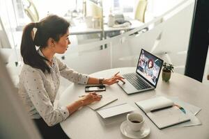 zakenvrouw gedurende online video conferentie met collega terwijl zittend in kantoor foto