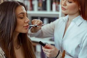professioneel bedenken artiest toepassen lip Gloss naar klant lippen Bij schoonheid salon foto