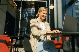 elegant bedrijf vrouw zittend in modern coworking en werken Aan laptop. hoog kwaliteit foto
