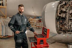 gebaard Mens vliegtuig monteur gebruik makend van gereedschap doos in hangar foto