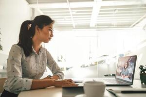 zakenvrouw gedurende online video conferentie met collega terwijl zittend in kantoor foto