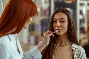 vrouw cliënt krijgen bedenken van professioneel bedenken artiest toepassen lip Gloss Aan haar lippen foto