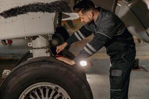 mannetje luchtvaart monteur repareren vliegtuig wiel in hangar foto