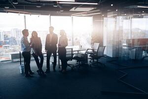 bedrijf team staand tegen panoramisch ramen in modern kantoor foto