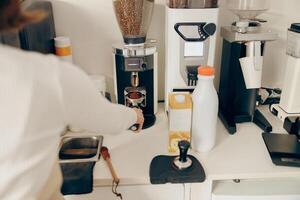 dichtbij omhoog van vrouw barista malen koffie Boon met Slijper machine terwijl werken in cafe foto