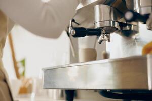 dichtbij omhoog van vrouw barista maken koffie in een koffie machine terwijl werken in cafe foto