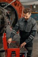 gebaard Mens vliegtuig monteur gebruik makend van gereedschap doos in hangar foto