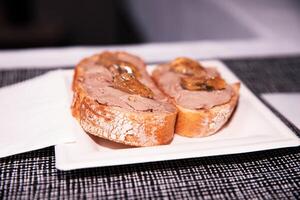 geroosterd brood bekroond met paté en gouden gelei Aan wit bord in restaurant foto