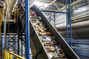 bewegende transportband op moderne afvalverwerkingsfabriek. gescheiden en sorteren van afvalinzameling. recycling en opslag van afval voor verdere verwijdering. foto