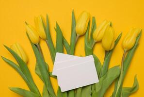 boeket van bloeiend geel tulpen met groen bladeren Aan een geel achtergrond foto