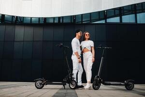 een meisje en een vent zijn wandelen Aan elektrisch scooters in de omgeving van de stad, een paar in liefde Aan scooters. foto