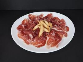 Iberico ham met knoflook geserveerd in een schotel geïsoleerd Aan donker achtergrond top visie foto