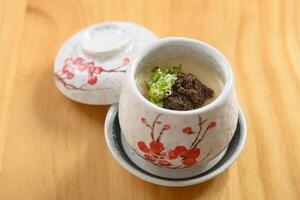 Japans voedsel truffel chawanmushi gestoomd ei geserveerd in een kom geïsoleerd Aan houten achtergrond top visie foto