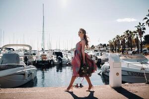 jong model- meisje in een mooi jurk met een boeket van bloemen Aan de strand in Frankrijk. meisje met bloemen in voorjaar provence Aan de Frans riviera foto