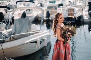 jong model- meisje in een mooi jurk met een boeket van bloemen Aan de strand in Frankrijk. meisje met bloemen in voorjaar provence Aan de Frans riviera foto