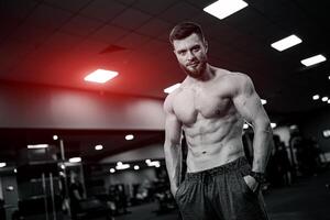 sterk atleet mannetje training in Sportschool. zonder shirt gespierd Mens hebben rust uit na moeilijk opleiding. foto