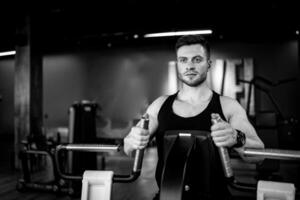 sportief Mens opleiding zijn lichaam Bij Sportschool. fit atletisch mannetje werken uit met gewichten. foto