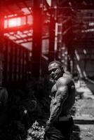 knap sterk bodybuilder buitenshuis op zoek naar zijn kant. zwart en wit afbeelding van gespierd Mens. foto