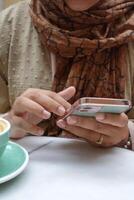 Dames hand- Holding slim telefoon zittend Aan cafe foto