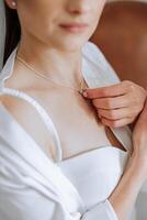 de bruid accenten de hanger Aan haar nek met haar vingers. voorbereiding voor de bruiloft. bruiloft viering. foto