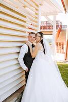 stijlvol, jong bruidegom en mooi bruid in een lang wit jurk en een lang sluier met een boeket in hun handen, knuffelen in de park in de herfst natuur. bruiloft portret van pasgetrouwden. foto