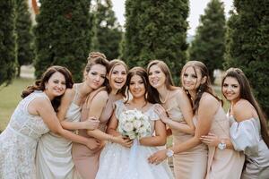 bruiloft fotografie. een brunette bruid in een wit jurk met een boeket en haar brunette vriendinnetjes foto