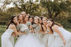 bruiloft fotografie. een brunette bruid in een wit jurk met een boeket en haar brunette vriendinnetjes foto