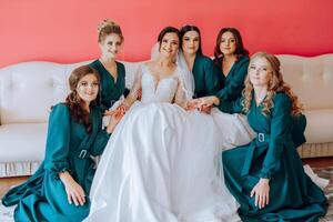 portret van de bruid met haar vrienden. elegant en elegant bruid met haar vrienden in bij elkaar passen jurken in de kamer in de ochtend. veel mooi meisjes in een foto. foto