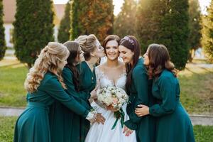bruiloft fotografie. een brunette bruid in een bruiloft jurk en haar vrienden in smaragd jurken foto
