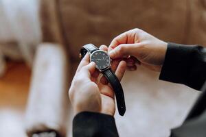 een detailopname van een bijgesneden kader van een Mens zet Aan een kijk maar met een leer riem, is gekleed in een elegant pak, een wit shirt, draagt een goud ring. foto