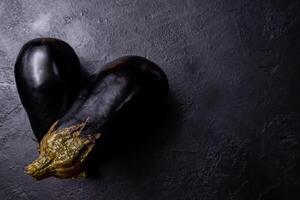 samenstelling van twee aubergines Aan een donker achtergrond. foto