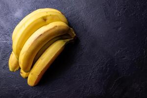 een bundel van bananen Aan een zwart tafel. foto