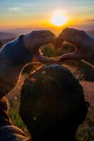 een jong meisje maken hart symbool met haar handen Bij zonsondergang foto