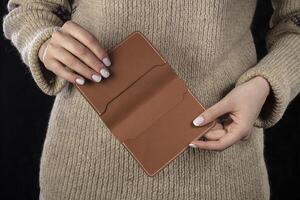 een bruin leer portemonnee is in vrouwen handen. foto