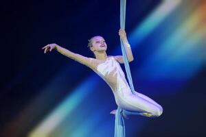 prestatie door een circus acrobaat artiest. meisjes uitvoeren antenne acrobatisch elementen Aan kleding stof. foto