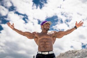 gespierd knap zonder shirt bodybuilder staand Aan een blauw lucht. geweldig atletisch jong vent met naakt torso. foto