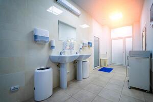 schoon openbaar ziekenhuis badkamer met leuning zeep en papier handdoek dispenser. foto