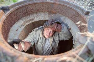 riolering werken. industrieel afvalwater behandeling. een arbeider in een riool broeden met een loodgieter sleutel. foto