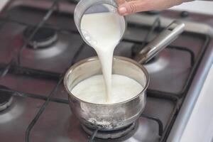 B' olie melk in een klein pan Aan de fornuis. bereiden melk pap. foto